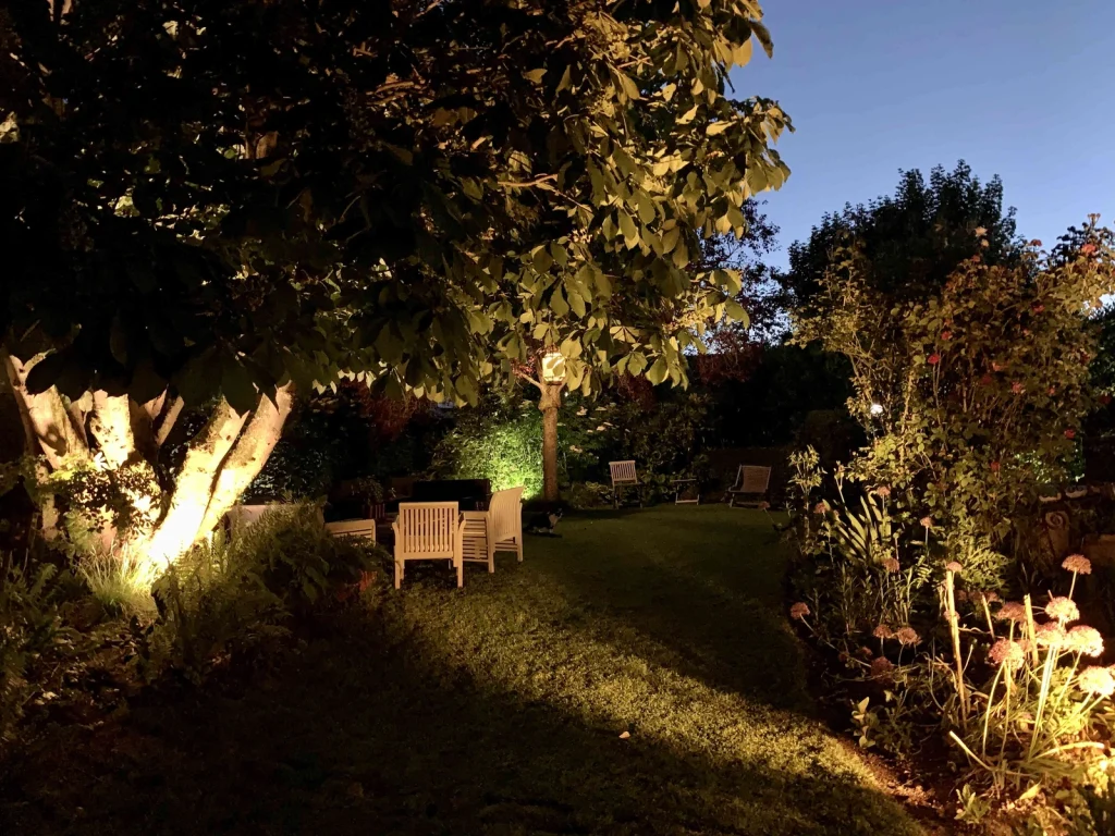 Le jardin illuminé en soirée, fauteuils et éclairage d'ambiance