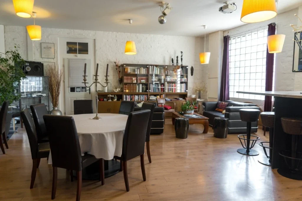 Salle de réception du Clos de Royaucourt aménagée pour un dîner de groupe, tables rondes dressées et grande table d'honneur